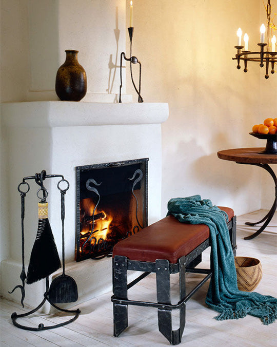 Wrought iron furniture fireside scene with wrought iron fireplace tools, iron bench, iron chandelier and iron table.