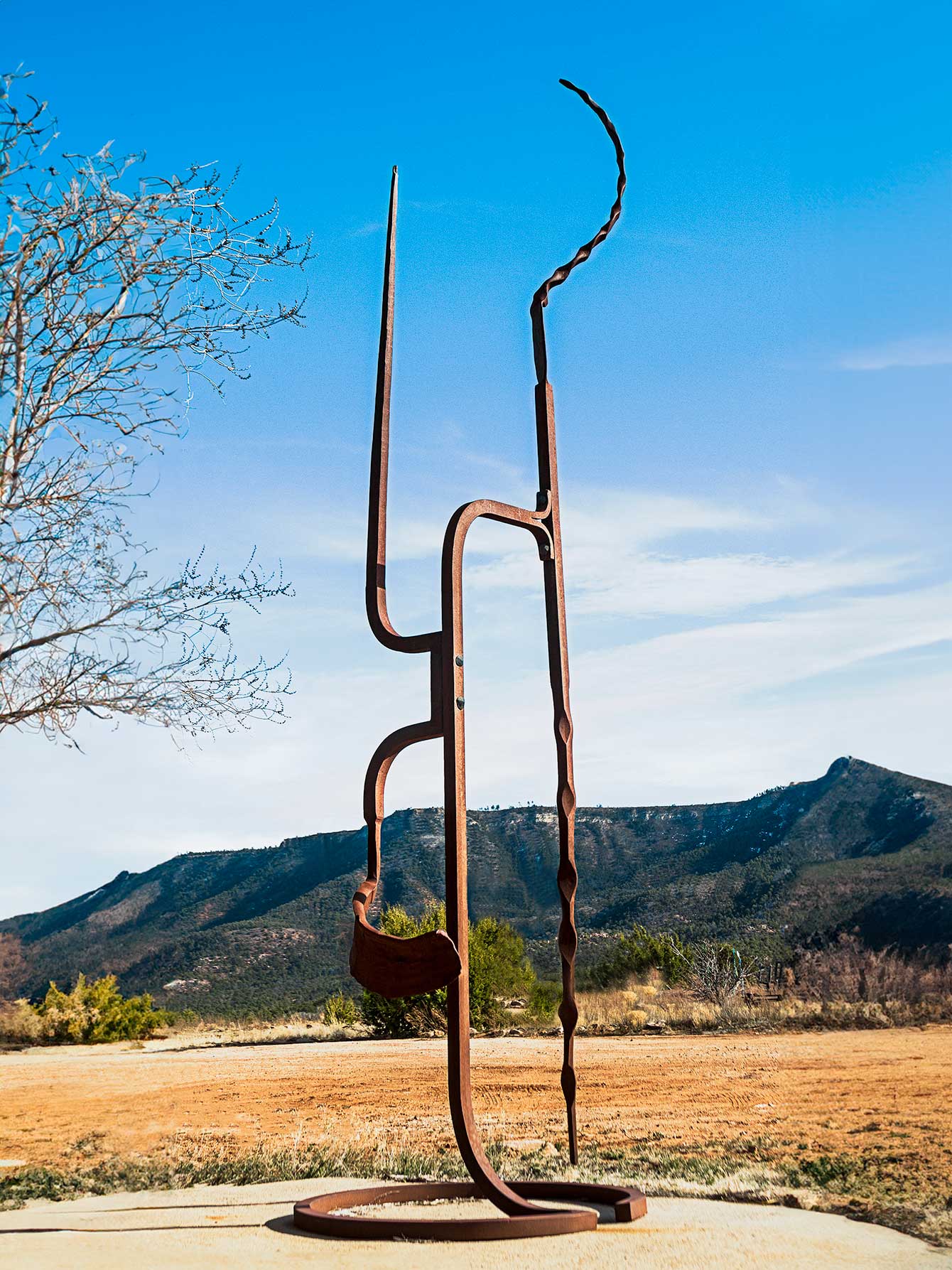 Large abstract bronze sculpture by Christopher Thomson. Sculpture is 12 feet high and stands on a cement platform in a scenic landscape.