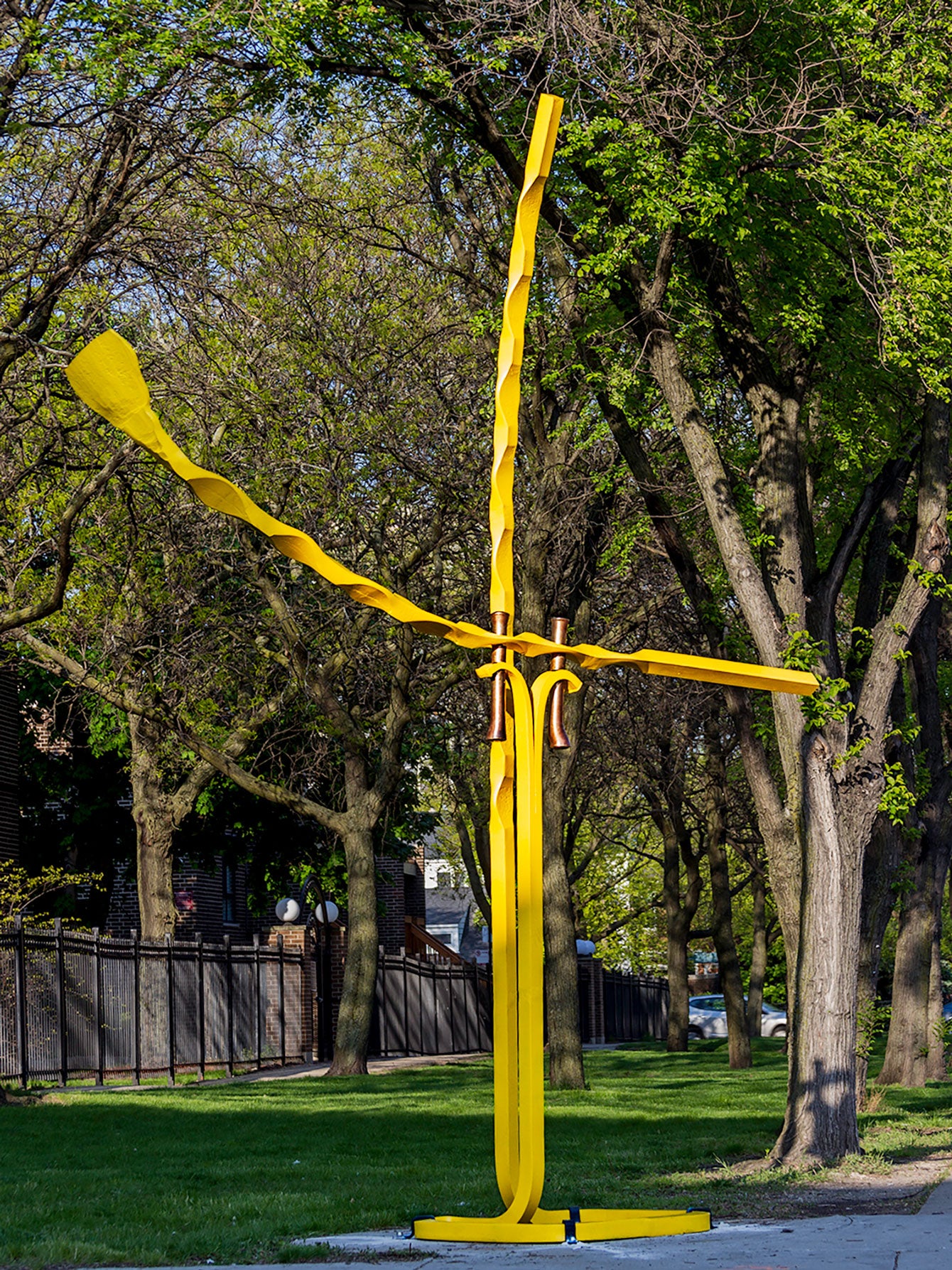A very large abstract, yellow sculpture that stands 16 1/2 feet tall. Sculpture is made of hand blacksmith Christopher Thomson.