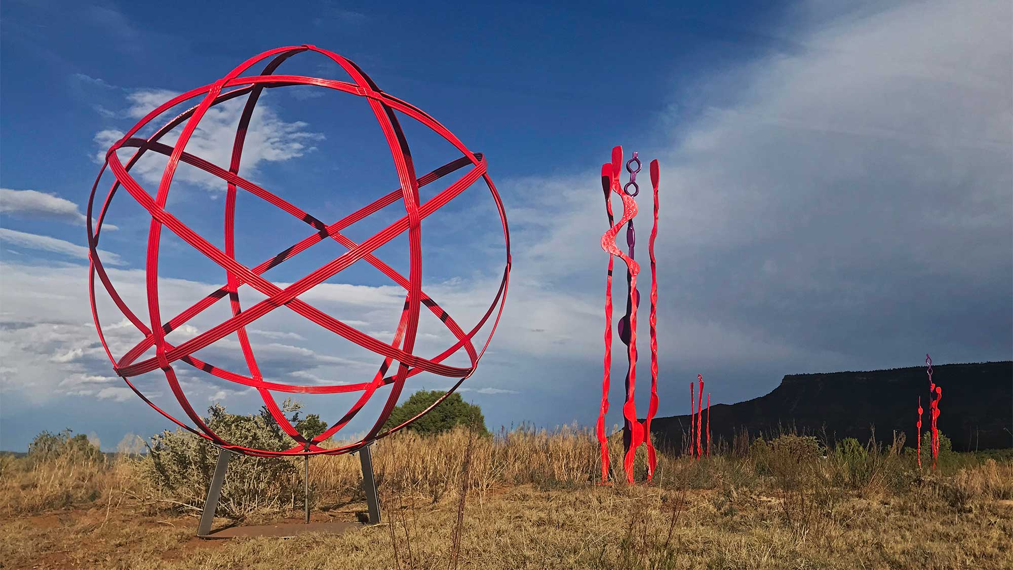 Large red steel sculptures scattered across the landscape.