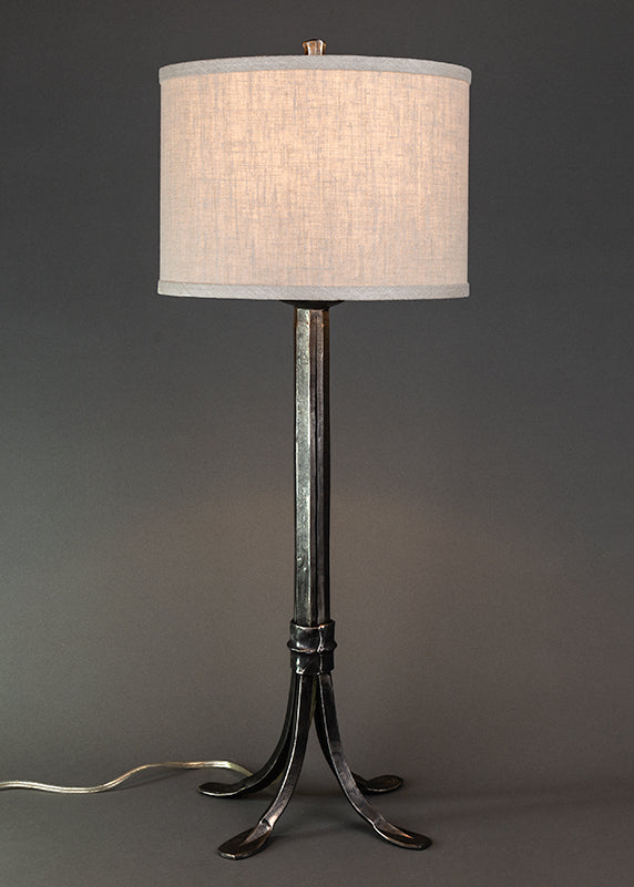 Wrought iron lamp with a metal sheave wrapped around the base. Shown with a linen drum shade. Lamp made by blacksmith, Christopher Thomson Ironworks.