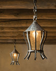 Two hanging lantern-style lights with a rustic design against an adobe wall.