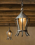 Two hanging lantern-style lights with a rustic design against an adobe wall.