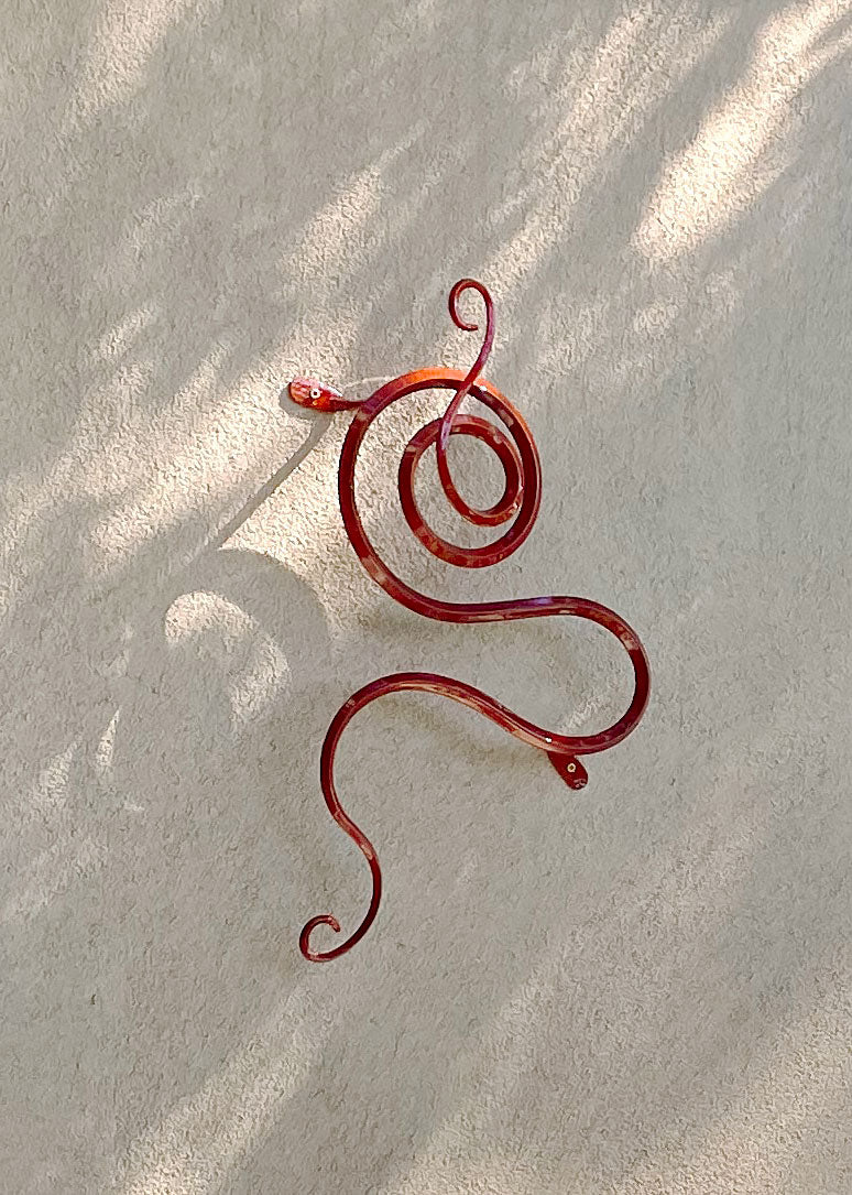 Red Copper metal wall sculpture on an outside adobe wall.