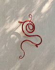 Red Copper metal wall sculpture on an outside adobe wall.