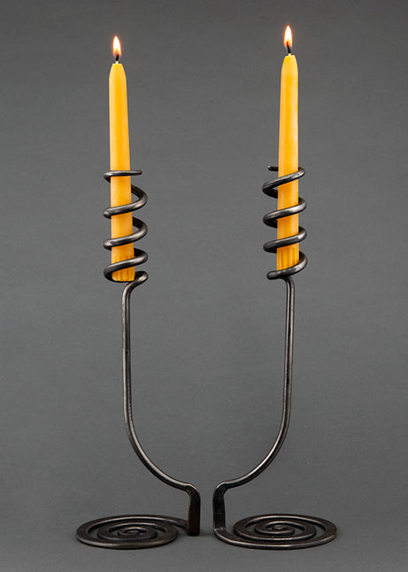 Wrought iron candle holders with a swirling base and a spiral design that wraps around taper beeswax candles.