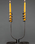 Wrought iron candle holders with a swirling base and a spiral design that wraps around taper beeswax candles.