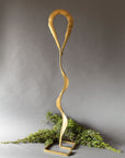 Gold metal sculpture with wavy design on a gray background
