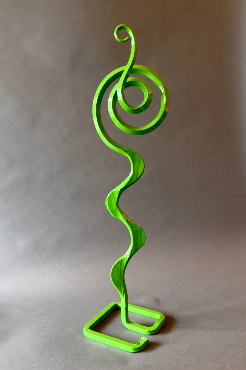 Hand-forged Green Carnival Mesa Bloom sculpture with vibrant curved metal elements, designed for outdoor garden art and landscape décor.