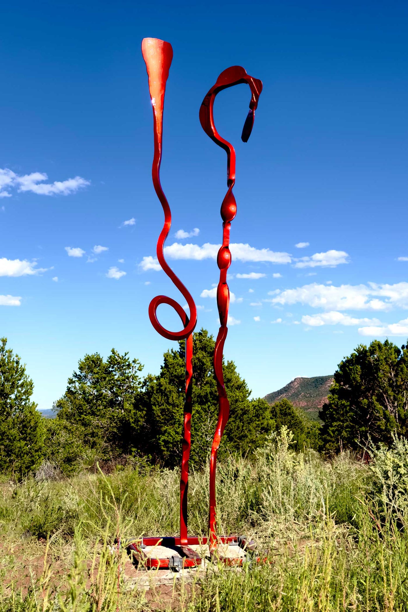 Red hand forged steel sculpture with two abstract elements.