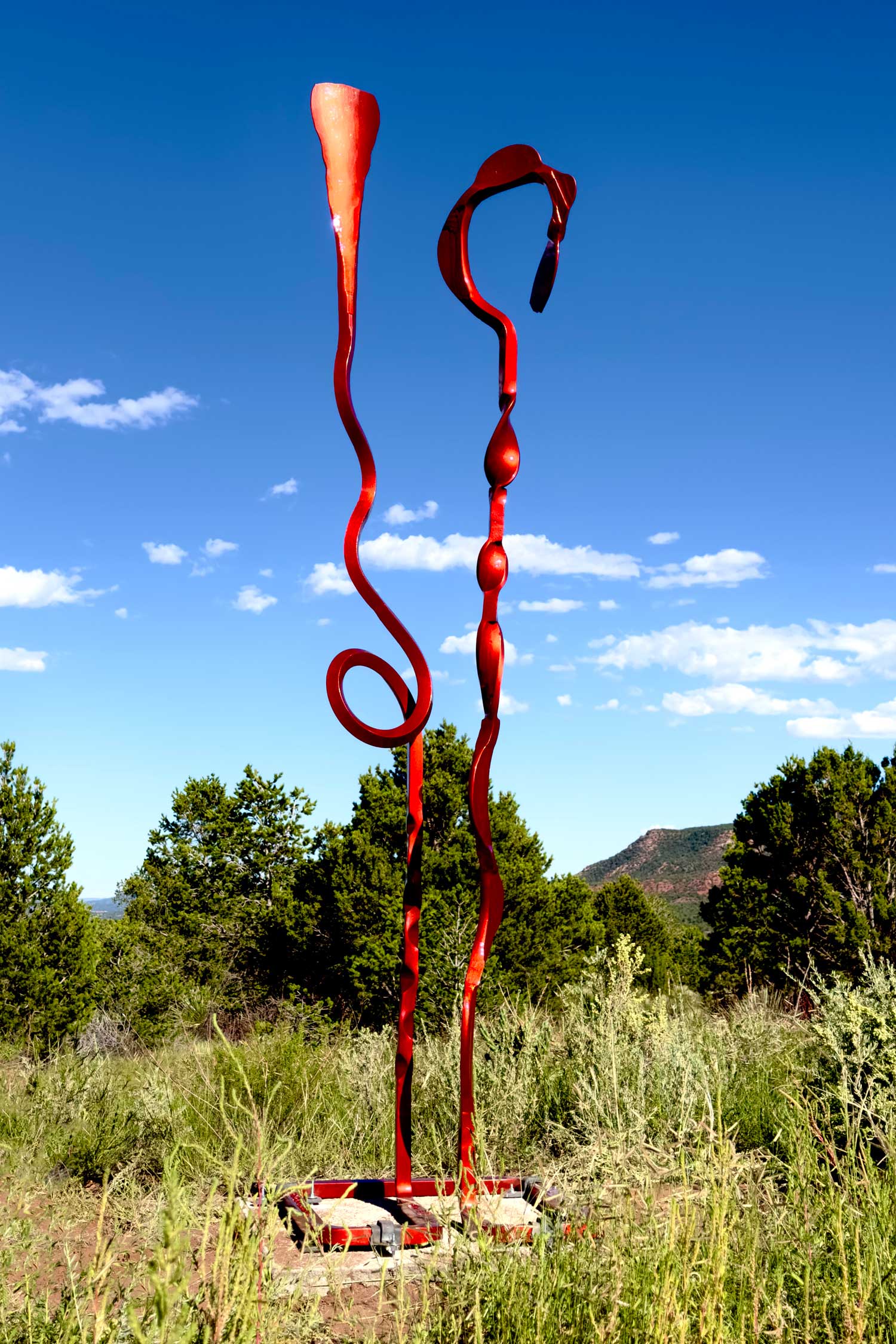 Red hand forged steel sculpture with two abstract elements.