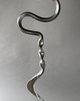 Metallic sculpture of a wavy, abstract design on a gray background