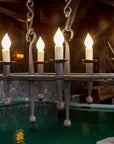Oval Rustic Fleur Wrought Iron Chandelier hanging above an indoor pond.