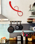 Red iron wall sculpture mounted to the wall above a kitchen counter.