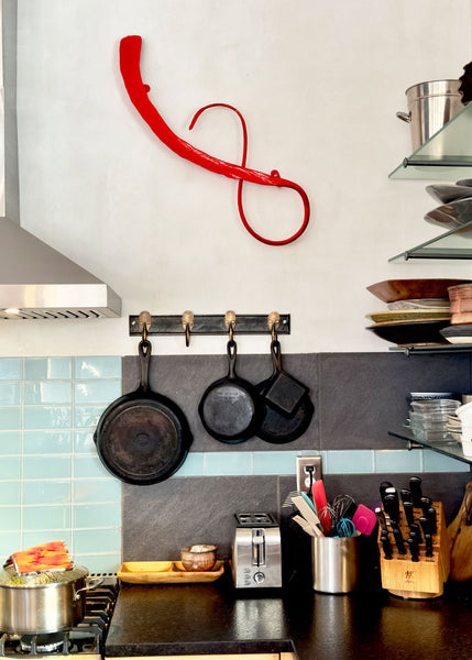 Kitchen counter scene with a red abstract metal wall sculpture. 