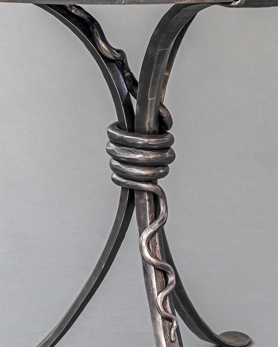 Iron forged rattlesnake wrapped around a wrought iron table base.