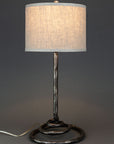 High end wrought iron lamp with a spiral base shown with a linen drum shade. Lamp made by blacksmith Christopher Thomson in New Mexico.