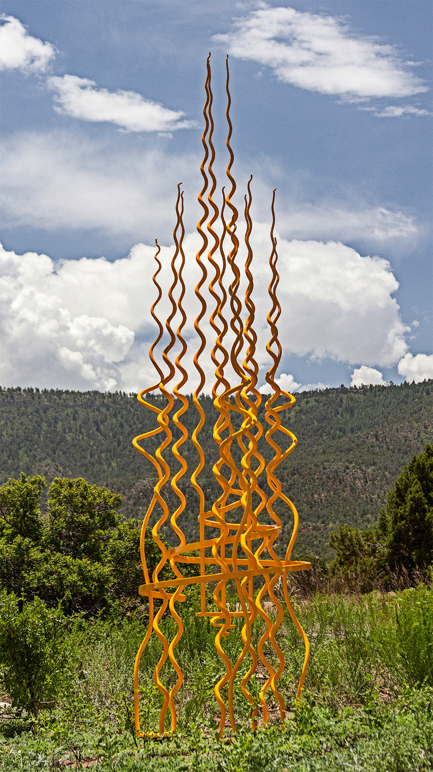 Large yellow sculpture in a mountain scape.