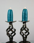 Two handmade wrought iron candlestick holders shown with blue beeswax candles.