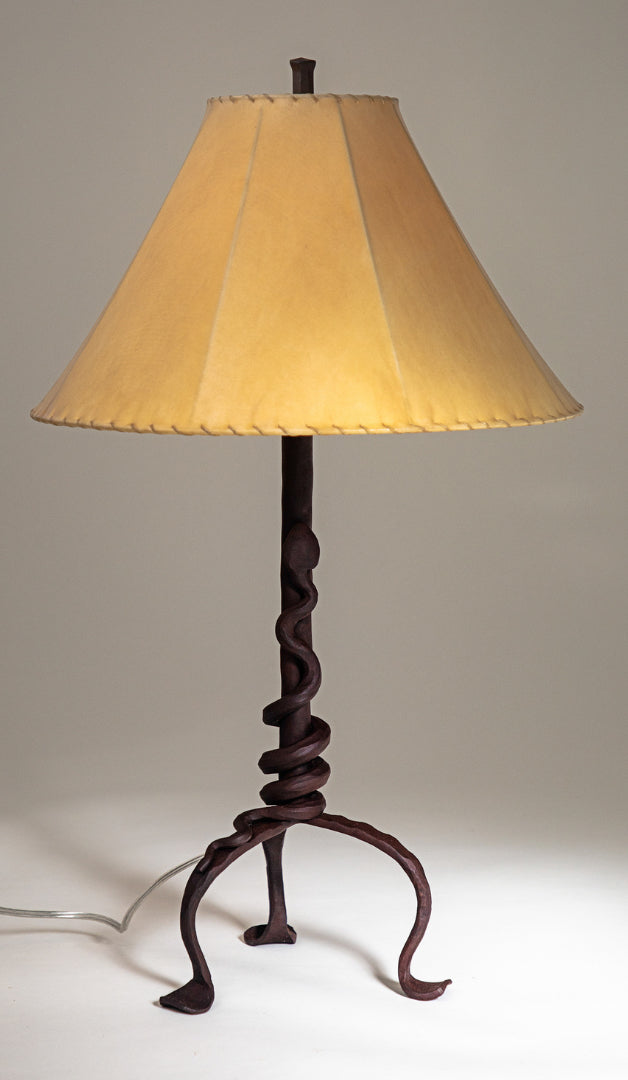 Western Rattlesnake wrought iron lamp with a forged steel rattlesnake wrapped tightly around the base of the light fixture's stem. Shown with a handmade sheepskin shade.