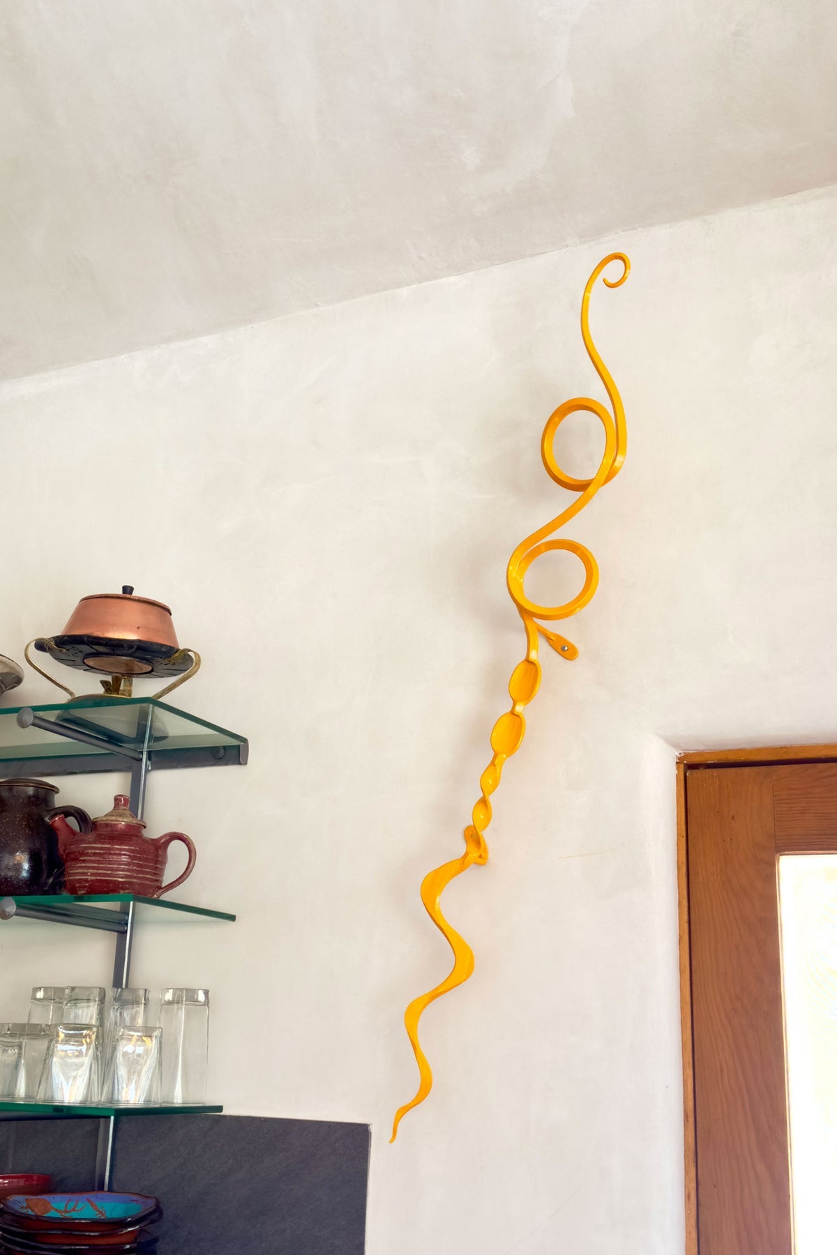 Yellow metal wall sculpture hanging in a kitchen.