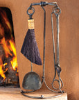 Wrought iron forged fireplace tool set standing next to a kiva fireplace.