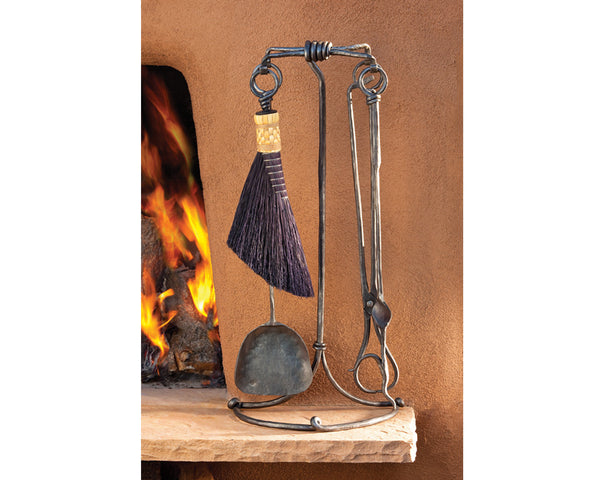 Wrought iron forged fireplace tool set next to a kiva fireplace.