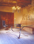 A rustic old world wrought iron dining table in a room decorated with high end forged steel furniture, iron chandelier and wrought iron candlestick holders by new Mexico blacksmith, Christopher Thomson.