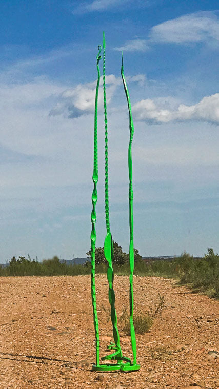 Green hand forged steel sculpture with three tall individual pieces attached to a free standing spiral base.