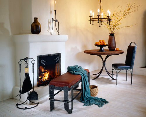 Fireside scene with wrought iron furniture and elegant iron home decor by Christopher Thomson, showcasing his hand forge Vessel Bench.