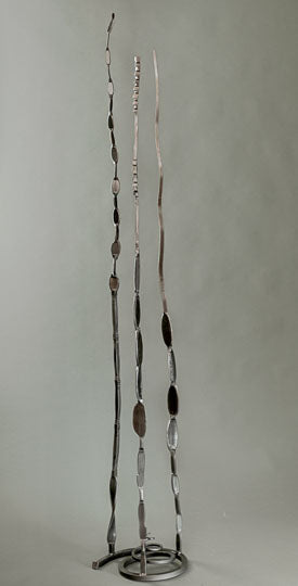 Slender and minimal abstract metal sculpture with a metallic finish. This forged steel sculpture has three vertical pieces of hand forged steel attached to a spiral base.