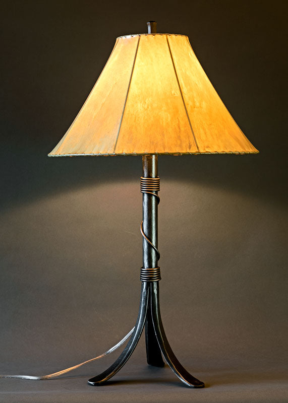 Twisted Valley Wrought Iron bedside lamp with a handmade sheepskin shade. Elegant wrought iron design Featuring a thin piece of twisted iron that wraps tightly around the base of the stem, loosening in the middle, and finishing tightly again at the top of the stem.