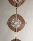 Three "Windings" sculptures hanging off each other forming a vertical column.