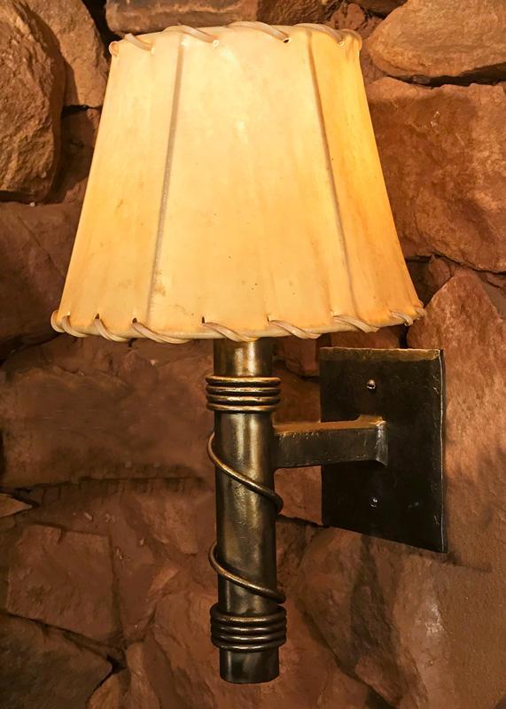 A small, rustic, forged steel Torch Wall Sconce with a rawhide sheepskin shade.