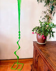 Indoor setting showing Green Beads Feather Free Standing Single Bloom sculpture next to indoor plants.