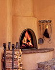 Outdoor wrought iron fireplace tools and accessories next to an outdoor kiva fireplace.