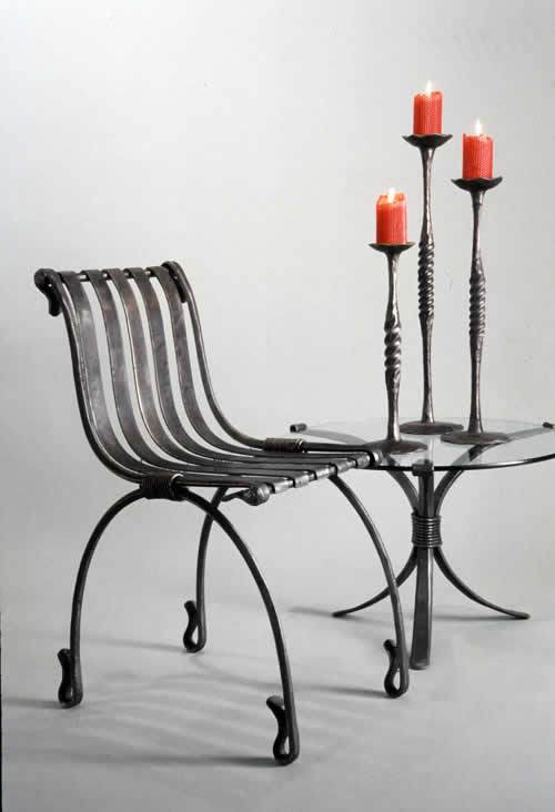 Wrought candle holders, on a forged steel table next to hand forged chair by award winning blacksmith from Santa Fe, New Mexico, Christopher Thomson.