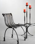 Wrought candle holders, on a forged steel table next to hand forged chair by award winning blacksmith from Santa Fe, New Mexico, Christopher Thomson.
