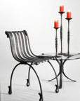 Wrought candle holders, on a forged steel table next to hand forged chair by award winning blacksmith from Santa Fe, New Mexico, Christopher Thomson.