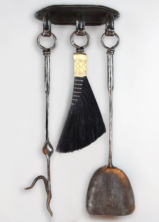 Wrought iron wall mounted fireplace tool set with a hand forged fire poker, broom and shovel.