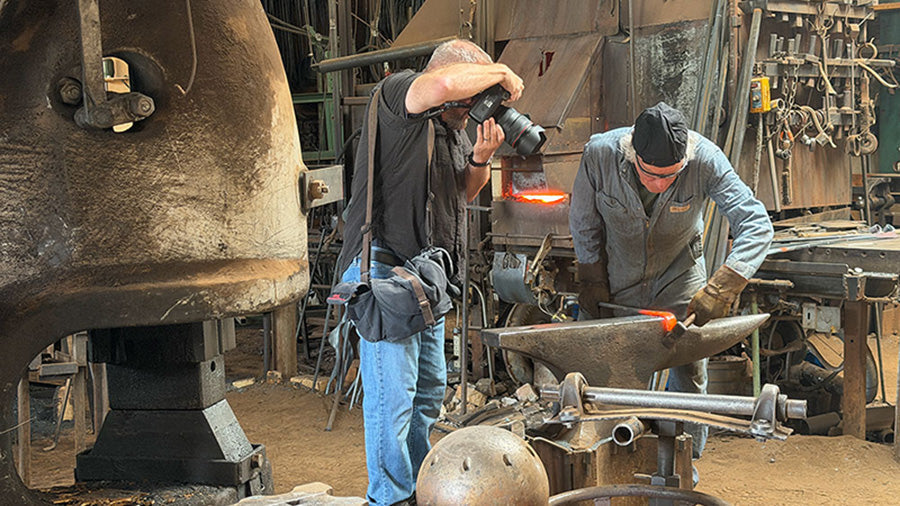Jim Weber photographing blacksmith, Christopher Thomson, hammering at the anvil in his blacksmith shop in New Mexico.