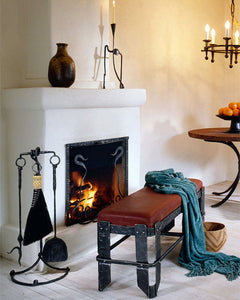 Wrought iron furniture fireside scene with wrought iron fireplace tools, iron bench, iron chandelier and iron table.
