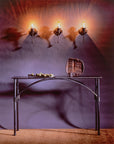 Wrought iron console table with an arched design underneath the table top. Hand forged table sits beneath three wrought iron light fixtures.