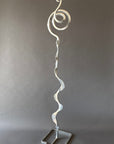 Chrome steel sculpture with a spiral design on a gray background