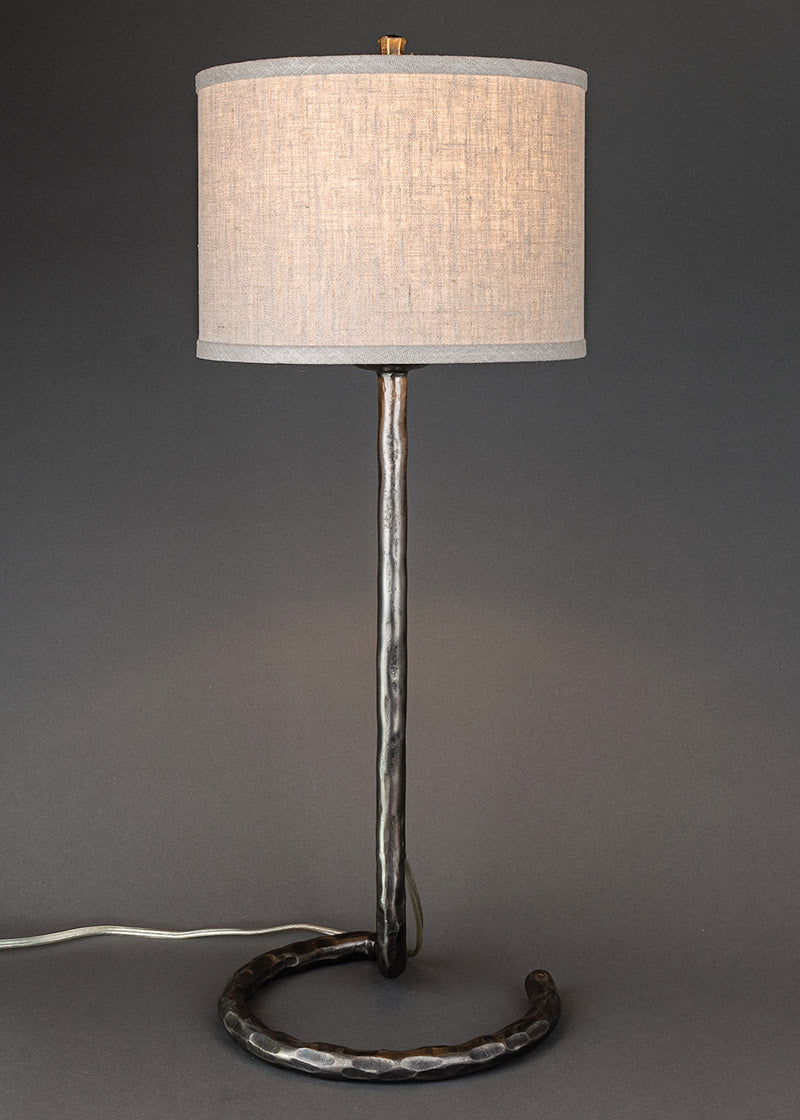 Wrought iron lamp with a circle base and a contemporary linen drum shade.