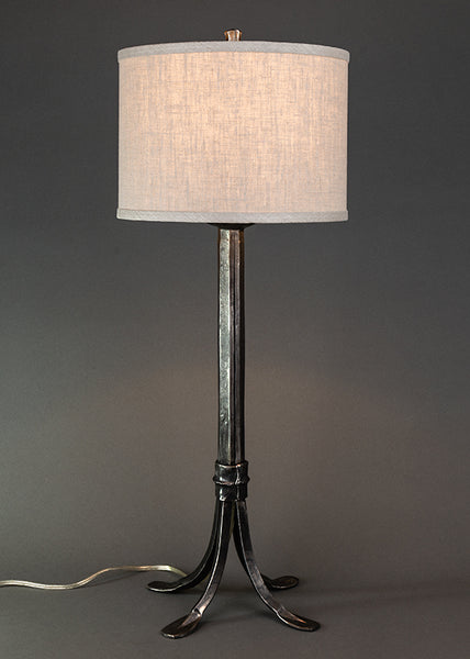 Wrought iron lamp with a metal sheave wrapped around the base. Shown with a linen drum shade. Lamp made by blacksmith, Christopher Thomson Ironworks. 