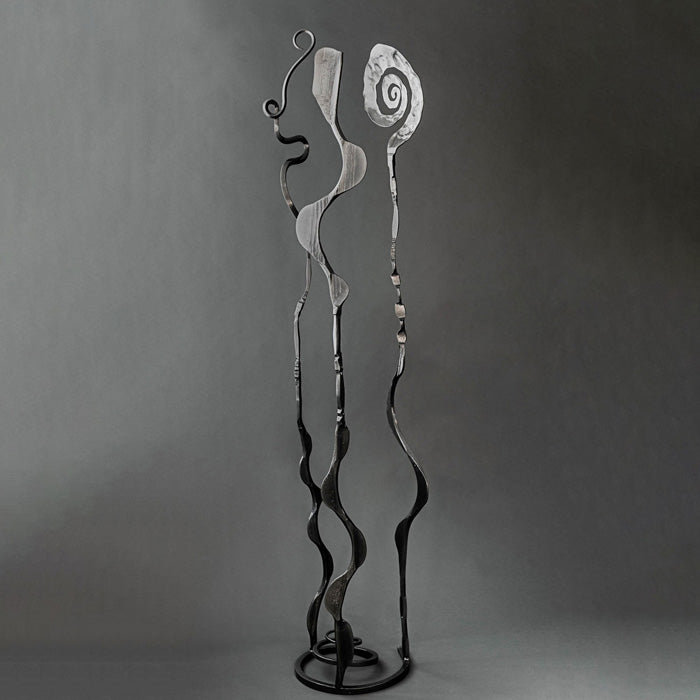 Abstract metal sculpture stand with two tall, wavy poles and spiral details on a dark gray studio background.