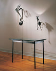 Modern glass top wrought iron writing table with decorative iron wall sconce and steel sculpture in a minimalistic setting. Hand forged ironworks by Christopher Thomson Ironworks.