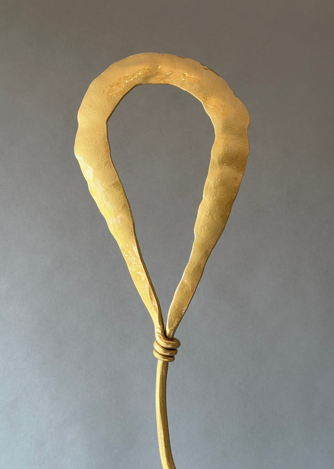 Gold metal balloon shape at the top of a sculpture.