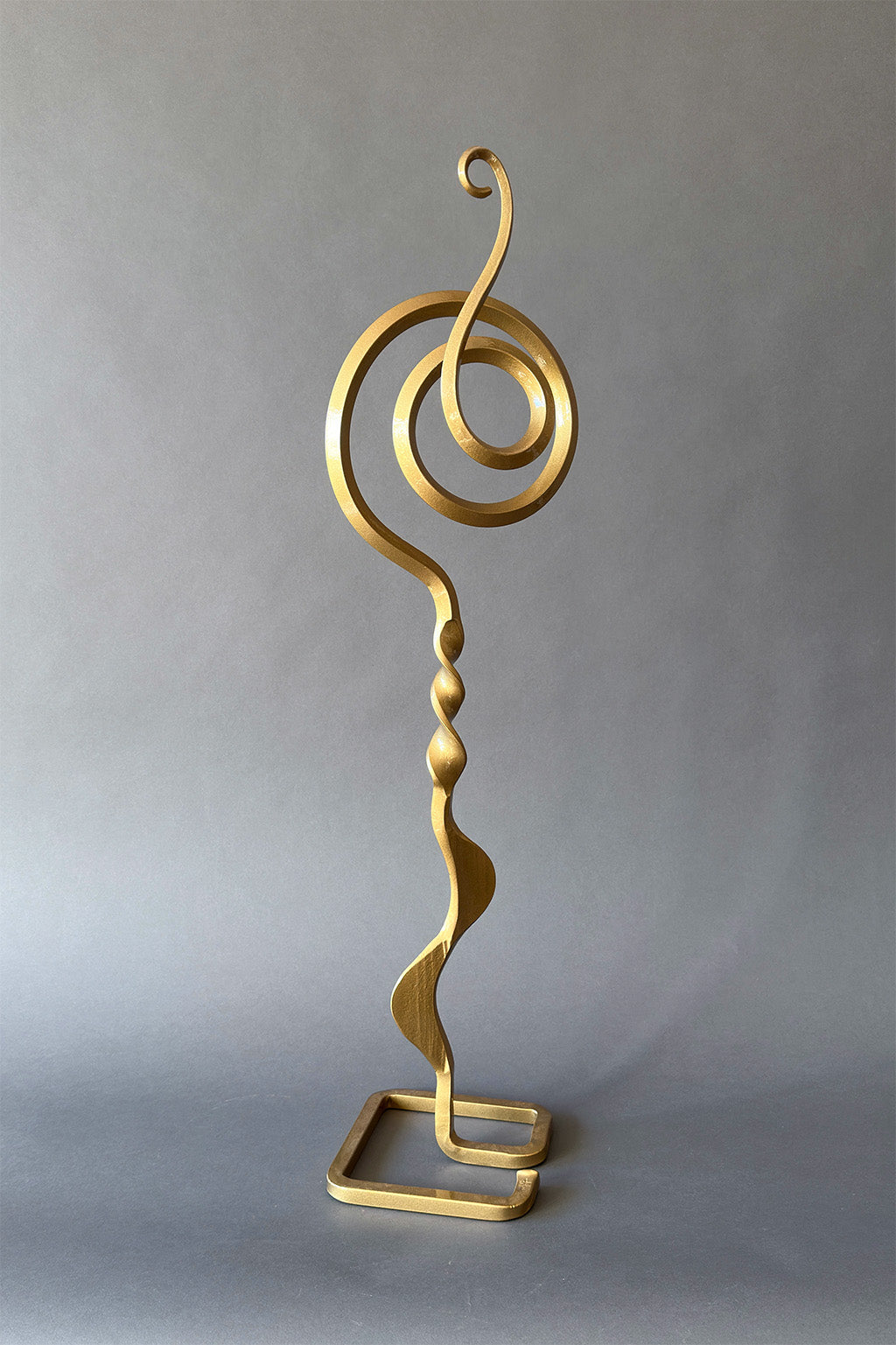 Gold abstract sculpture on a gray background